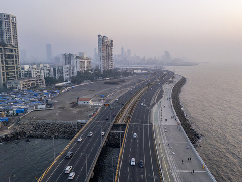 Aerial view of the cinematic Worli Seaface promenade curving along the Arabian Sea, with the Bandra Worli Sea Link stretching towards the Mumbai skyline, Worli, Maharashtra, India.