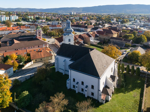 Aerial view of the white Cathedral of the Assumption of the Blessed Virgin Mary stands majestically against the backdrop of the city's terracotta roofs, Roznava, Kosice Region, Slovakia.