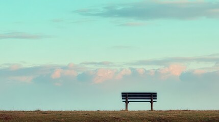 Tranquil outdoor scene featuring a solitary park bench against a pastel sky filled with soft clouds, evoking a sense of peace and serenity.