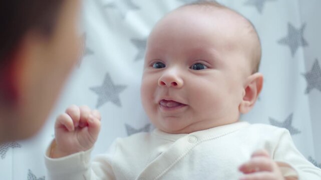 Newborn baby in her mother's arms. Mom holds the baby in her arms. The child looks into the camera.  Infant with blue eyes.