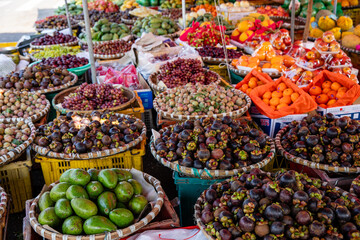 Obraz premium Colorful assortment of fresh fruits displayed in woven baskets at a vibrant outdoor market in Southeast Asia