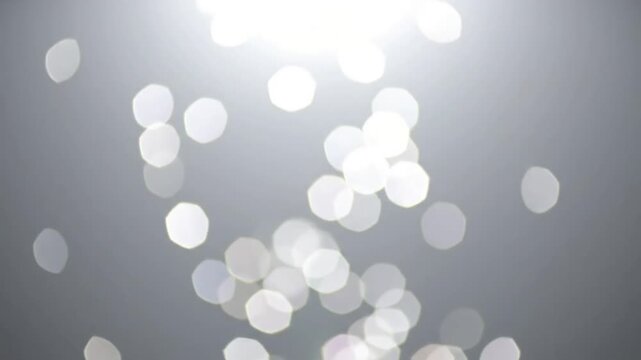 Dynamic Light Beam Bokeh A more active display of top light bokeh, with light particles appearing to 'fall' or drift downwards, creating a beautiful blurred effect against a clean void.