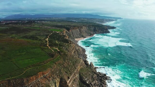 Drone is flying over the  rocky Atlantic ocean coastline, Portugal. Summer. Cloudy sky. Beautiful aerial view natural landscape with ocean rocky shore.  Scenic tourist travel destination. No people