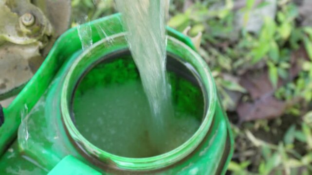 Water Pouring into Green Container from Pump