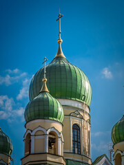 Vibrant image of an Orthodox church with striking green domes against a clear blue sky. Detailed architecture golden crosses.