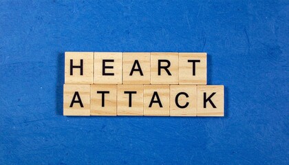 Wooden tiles spelling heart attack on blue surface background with scrabble style letters emphasizing medical awareness concept and design