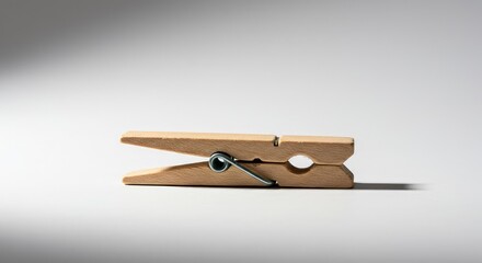 A classic wooden spring-type clothespin, simple and essential tool for drying laundry, placed against a bright white background ,sustainability ,retro ,friendly