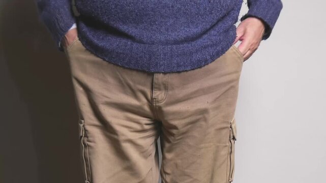 Close view of a person pulling out empty pockets to show lack of money, symbolic gesture of financial problems, poverty, or economic crisis, simple background suitable for finance and social themes