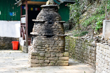 Traditional stone shrine structure in village courtyard, rustic architecture, cultural heritage site in Sikkim. 