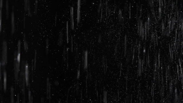 Tiny snow or dust randomly flying in the smoky air, empty space template for objects advertisement. Many dust particles cloud of white powder in low light on empty dark black contrast background.