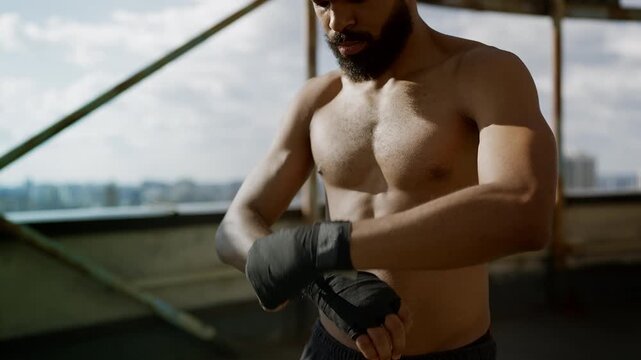 African American rooftop boxer wrapping hands before starting intense training