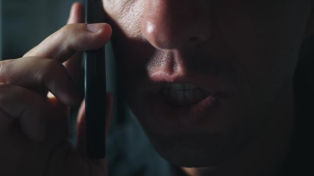 Extreme closeup angry millennial man shouting into smartphone in dark dramatic light. Concept aggression rage conflict toxic communication stress dominance emotional pressure modern male confrontation