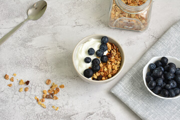 Breakfast Bowl with Yogurt, Granola and Blueberries with bowl of berries on gray background