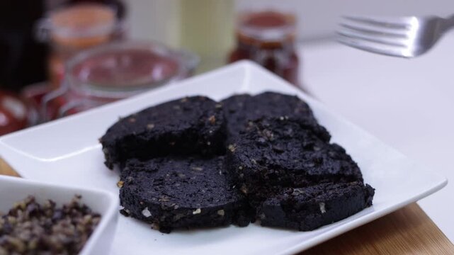 Silver fork cutting a piece of black pudding food
