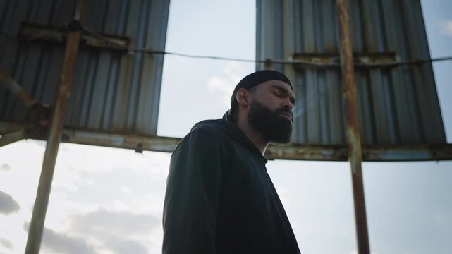 African American man in durag smoking cigarette on rooftop, bad boy concept