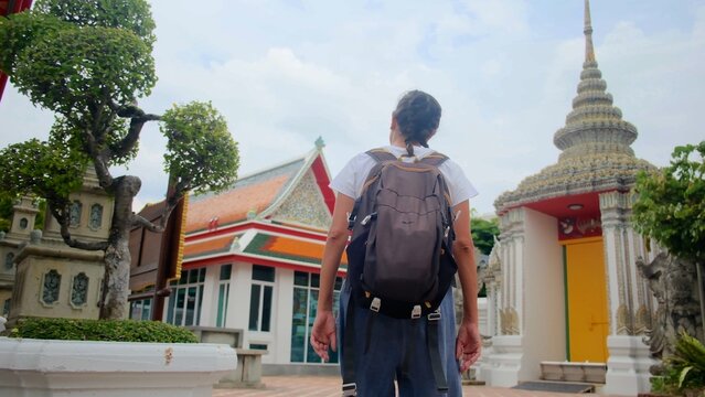 Backpacker exploring ancient buddhist temple grounds, immersing in thai culture and spiritual architecture, enjoying a travel journey through historical sites in bangkok