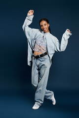 Elegant young woman showcases trendy oversized denim fashion in a vibrant studio scene