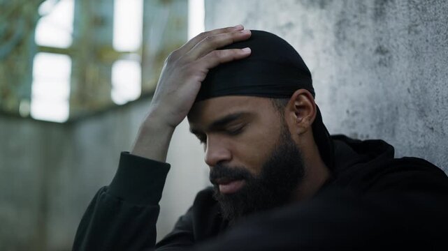 Black man suffering depression while sitting alone on rooftop, financial stress