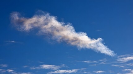 Fototapeta premium A white and grey smoke plume drifts across a vibrant blue sky on a sunny day
