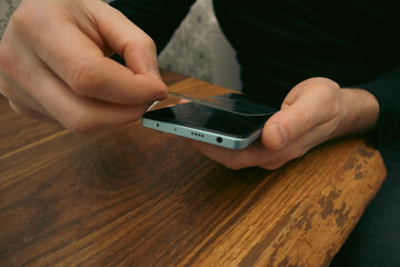 Man applying a protective tempered glass film to a smartphone screen.
