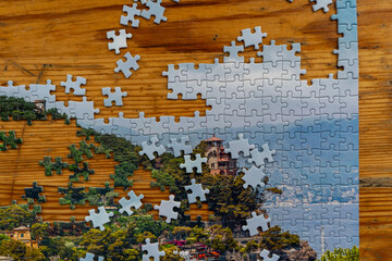 White and blue puzzle pieces forming partial image on wooden surface. Symbol of connection, partnership, innovation and strategic thinking in business environment.