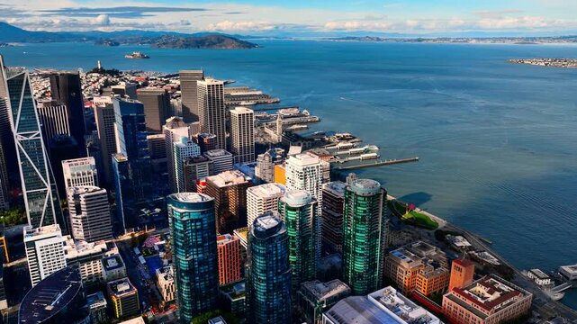 Aerial view of the San Francisco skyline near the waterfront. Various piers, shipping vessels in the bay, and modern skyscrapers with older urban structures. Alcatraz island.