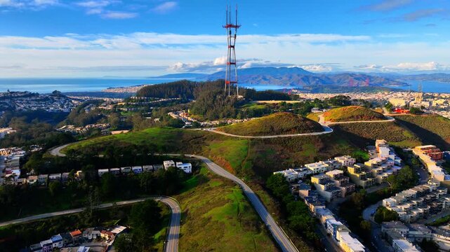 Sutro Tower broadcasting antenna located on Twin Peaks in San Francisco, California. The surrounding green hills, residential neighborhoods, and the Golden Gate Bridge. Aerial view.