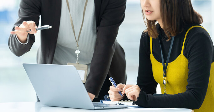 ノートパソコンを見ながら業務内容を確認・共有するビジネスシーン, Business professionals reviewing and sharing work on a laptop in the office