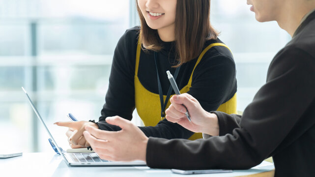 ノートパソコンを見ながら業務内容を確認・共有するビジネスシーン, Business professionals reviewing and sharing work on a laptop in the office