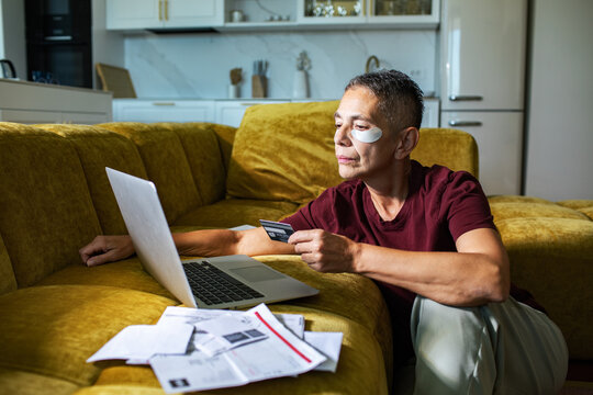 Mature person using laptop and credit card to pay bills at home