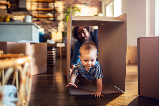 Baby crawling in a cardboard box while parent plays at home