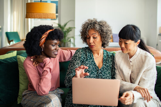 Three women collaborating on a laptop in a living room