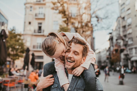 Father carrying daughter on shoulders in city street