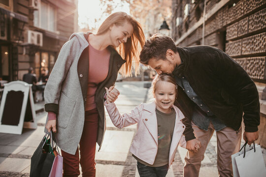 Parents and daughter shopping together on a sunny city street