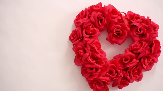 4K vertical video of a vibrant red rose heart arranged on a soft neutral background with generous copy space