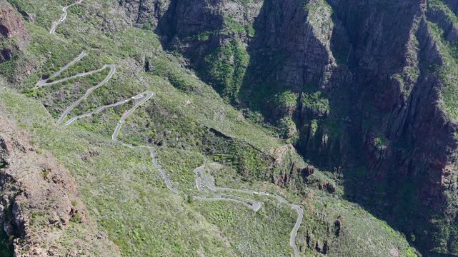 Cinematic aerial of the winding mountain road switchbacks leading to Masca village in Teno Rural Park Tenerife