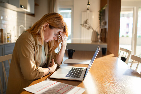 Stressed woman reviewing bills at home kitchen table