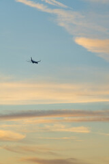 Airplane silhouette against colorful sunset clouds, Vertical