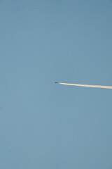 Airplane leaving white contrail across clear blue sky, Vertical
