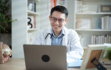 Fototapeta premium Asian male doctor in white coat having teleconference with patient.
