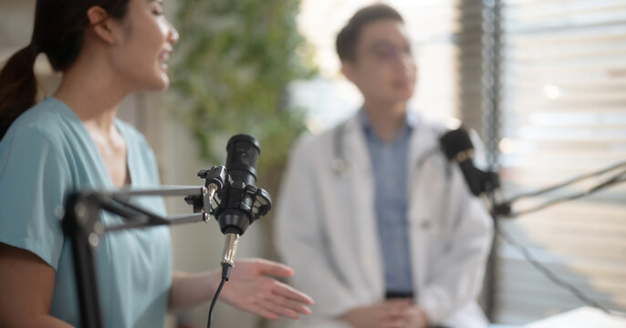 Asian male and female doctors hosting medical podcast together.