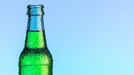 Close up of a green glass bottle with water drops. Refreshing cold drink on a light blue background. Beverage concept for summer.