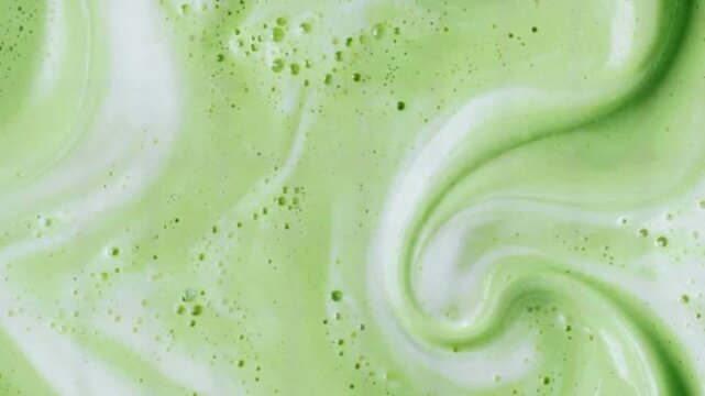 Macro close up of smooth matcha cream or green skincare lotion swirls, silky texture with bubbles background