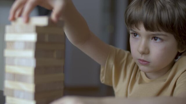 Child Having Fun Building Constructor Tower of Wooden Blocks. Boy Playing Wooden Block Tower Game at Home. Board Creative Game. Child Development Education Leisure. Play With Wooden Building Blocks.