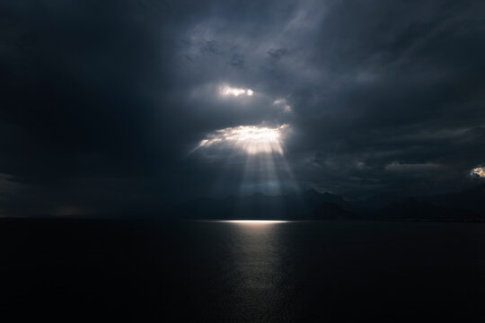 Dramatic light beams between clouds above ocean