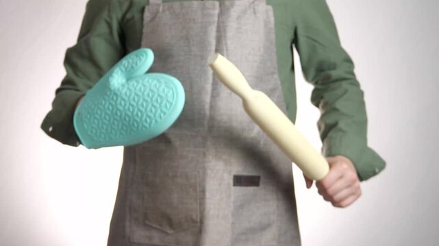 This closeup showcases the hands of a cook or baker presenting key tools: a protective silicone glove and a classic rolling pin. It embodies preparation, skill, and the tactile nature of food
