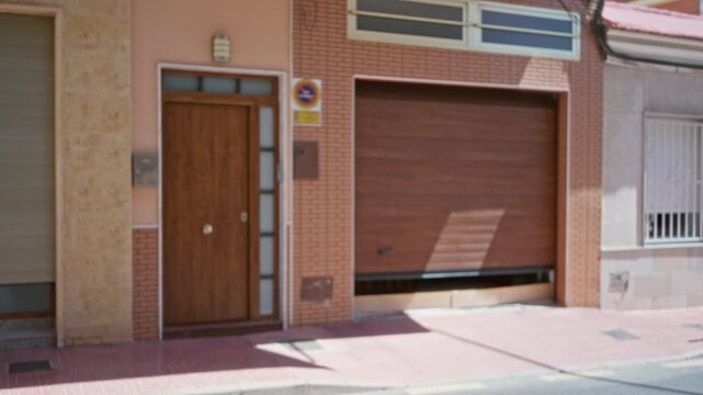Blurred street entrance with soft bokeh and shallow defocus, wooden door and garage on brick facade outdoor; background backplate copyspace calm.