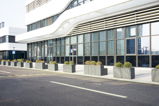 Modern hospital building facade with glass curtain wall and green planters along the street