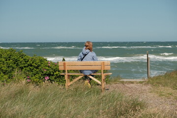 Fototapeta premium Frau blickt auf das Meer – entspannter Sommermoment an der schwedischen Küste, Natur und innere Ruhe.