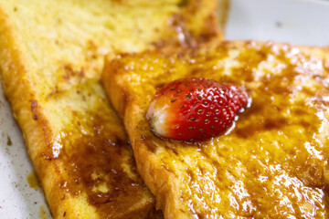 Delicious Caramel French Toast Topped with Fresh Strawberry and Mint Leaf Garnish on a White Plate © Jaenal Jalalludin